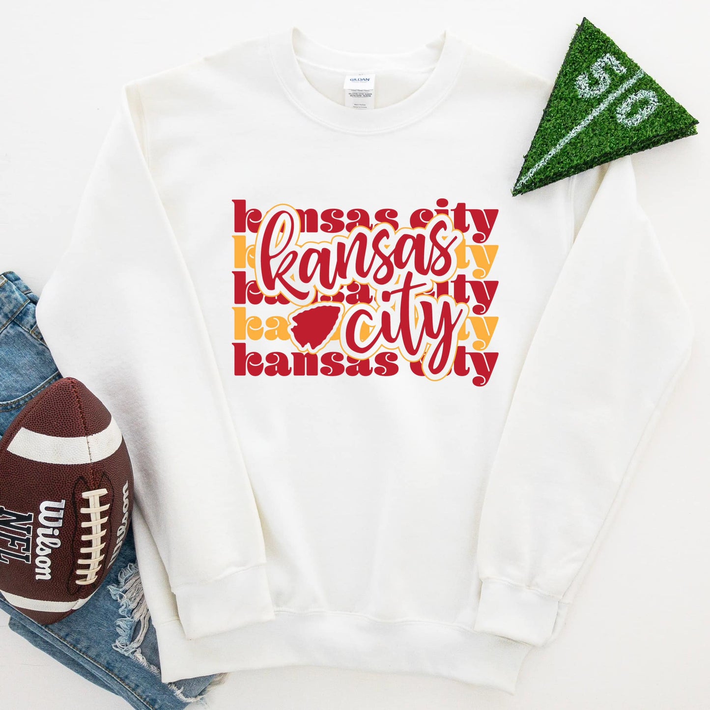 The product photo provided is only a mock up of the design. The design print is red and gold in colors and has the words Kansas City in alternating red and gold colors for the background. Over top of the background the words Kansas City is in red with a red arrowhead.