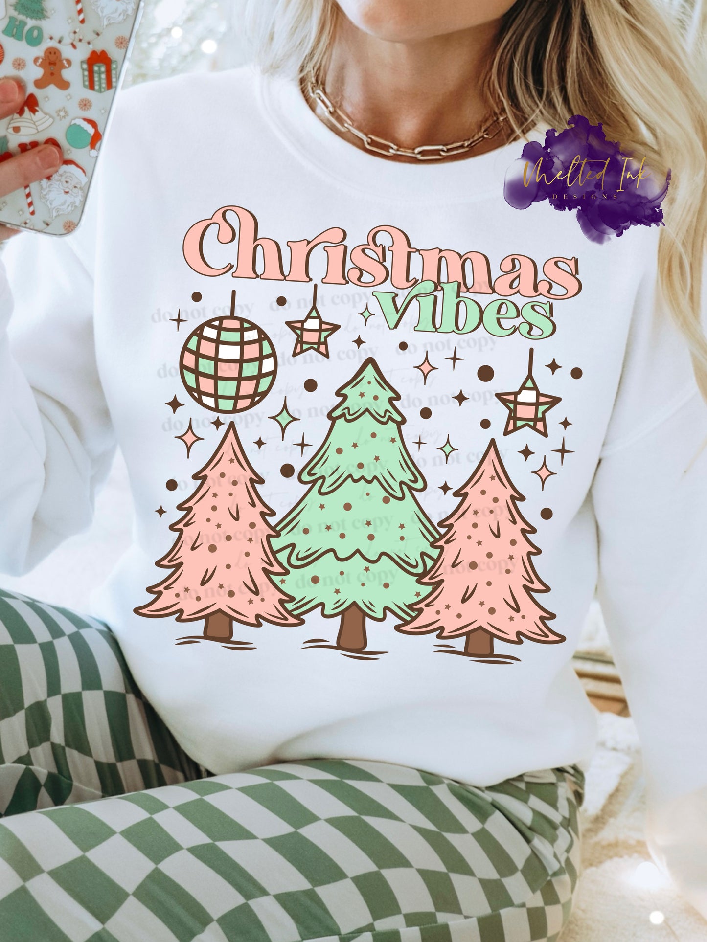 Photo is of a mock up of design and is on a white sweatshirt. Design is of pink and green Christmas trees and says Christmas Vibes.