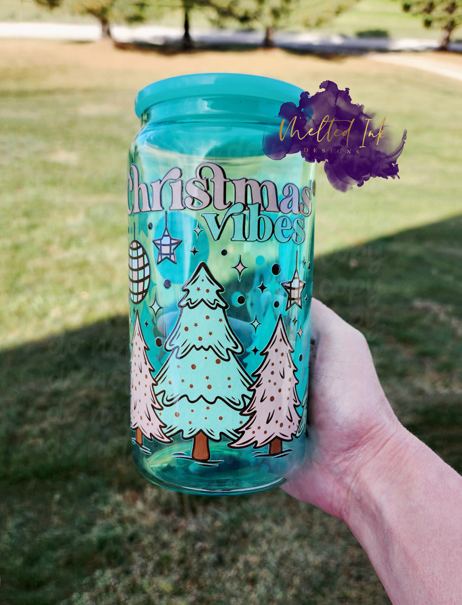 Photo is a picture of a aqua glass can with a uv dtf wrap of pink and mint colored christmas trees and it says Christmas Vibes.