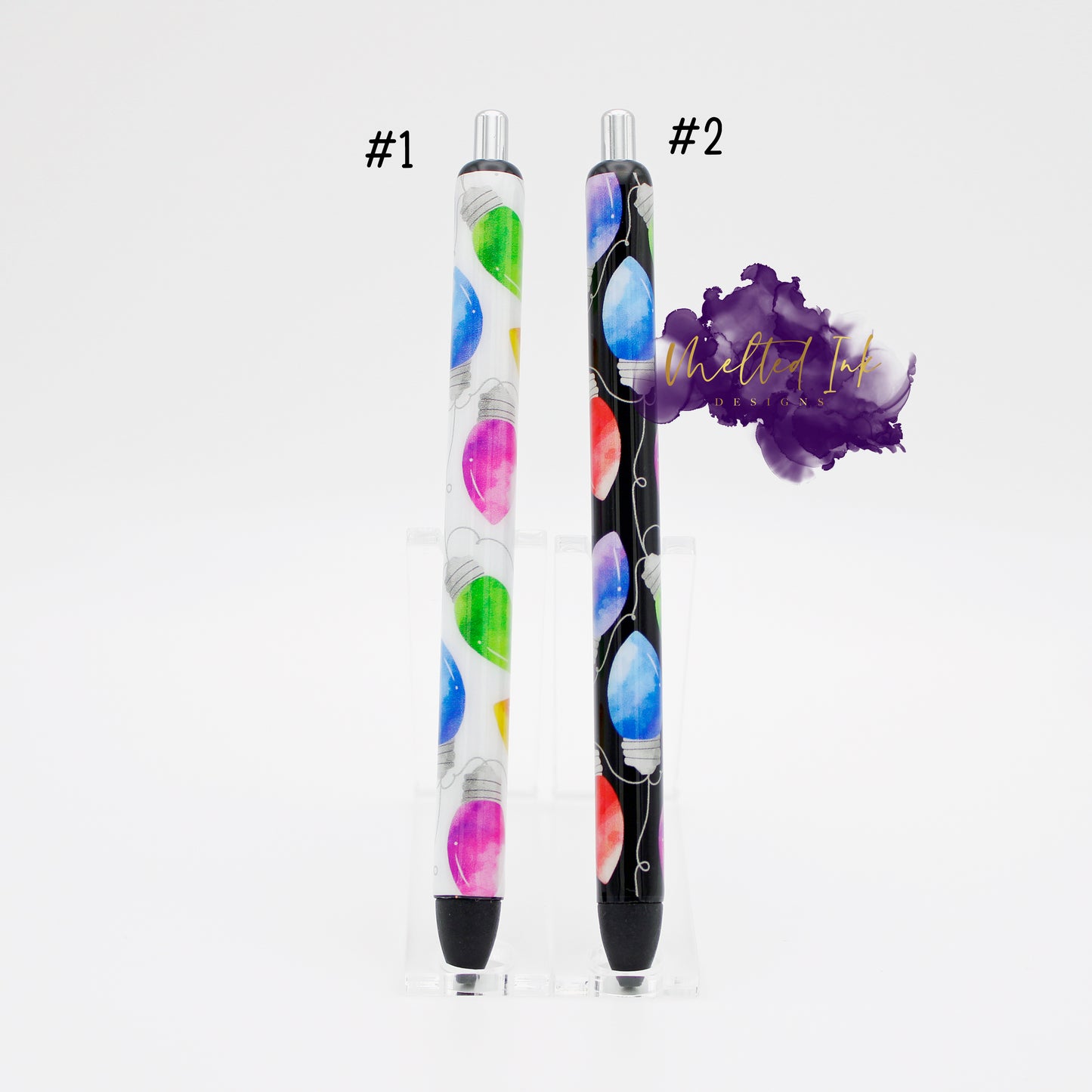 Photo has 2 different epoxy pens. #1 has a white background with different colored Christmas bulbs and #2 has a black background with different colored Christmas bulbs. Both comes with black ink.
