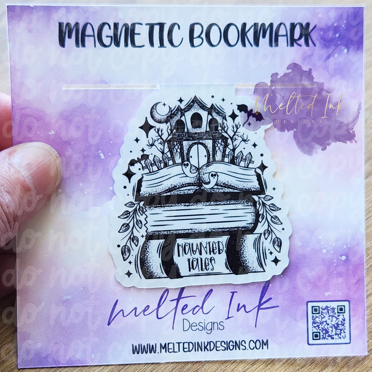 his magnetic bookmark is themed around spooky storytelling, featuring the phrase "Haunted Tales." It showcases a charming stack of books, topped with a cute little haunted house. Surrounding the house are playful little ghosts and bats, creating an enchanting and whimsical atmosphere.