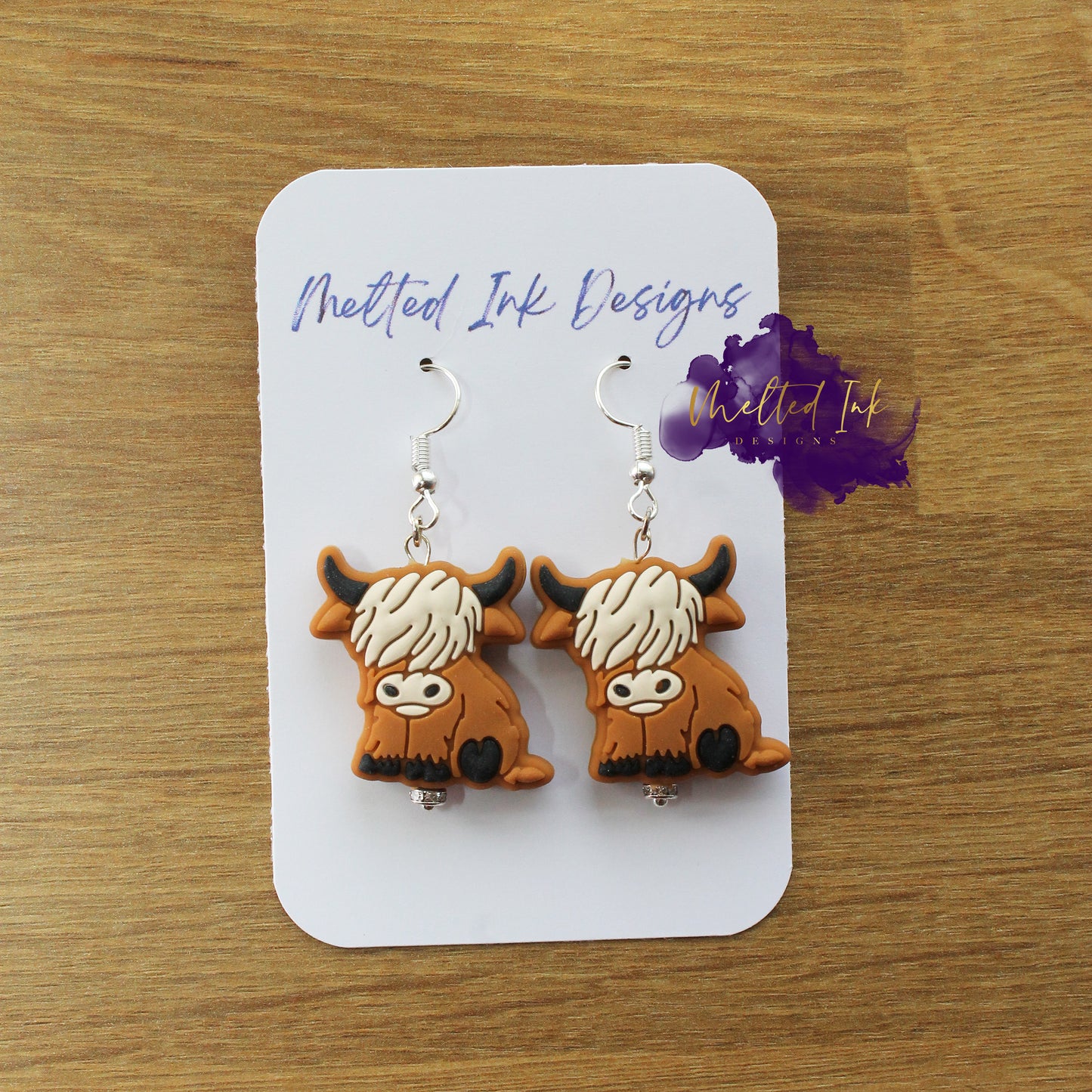 Photo is a picture of a pair of brown/tan highland cow earrings.