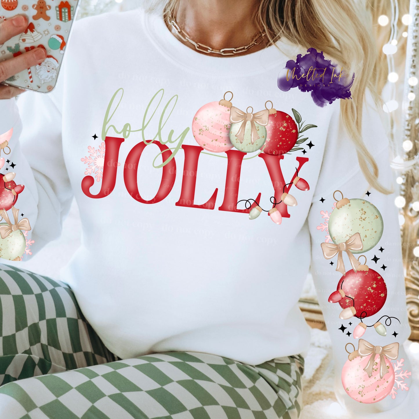 Design is a mock up and is on a white sweatshirt. Design says Holly in green color and Jolly is in red. Design has a picture of pink, red and green ornaments. Also has option of sleeve design that has same colored ornaments.