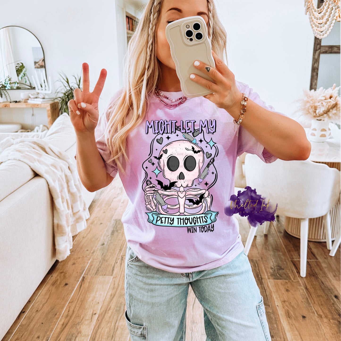 Photo is a mock up of the design. Design print is colored and is pressed on a lavender shirt. Design says Might Let My Petty Thoughts Win Today. Has a picture of a skeleton holding a knife. In the background has hearts, stars, bats and a couple knives floating.