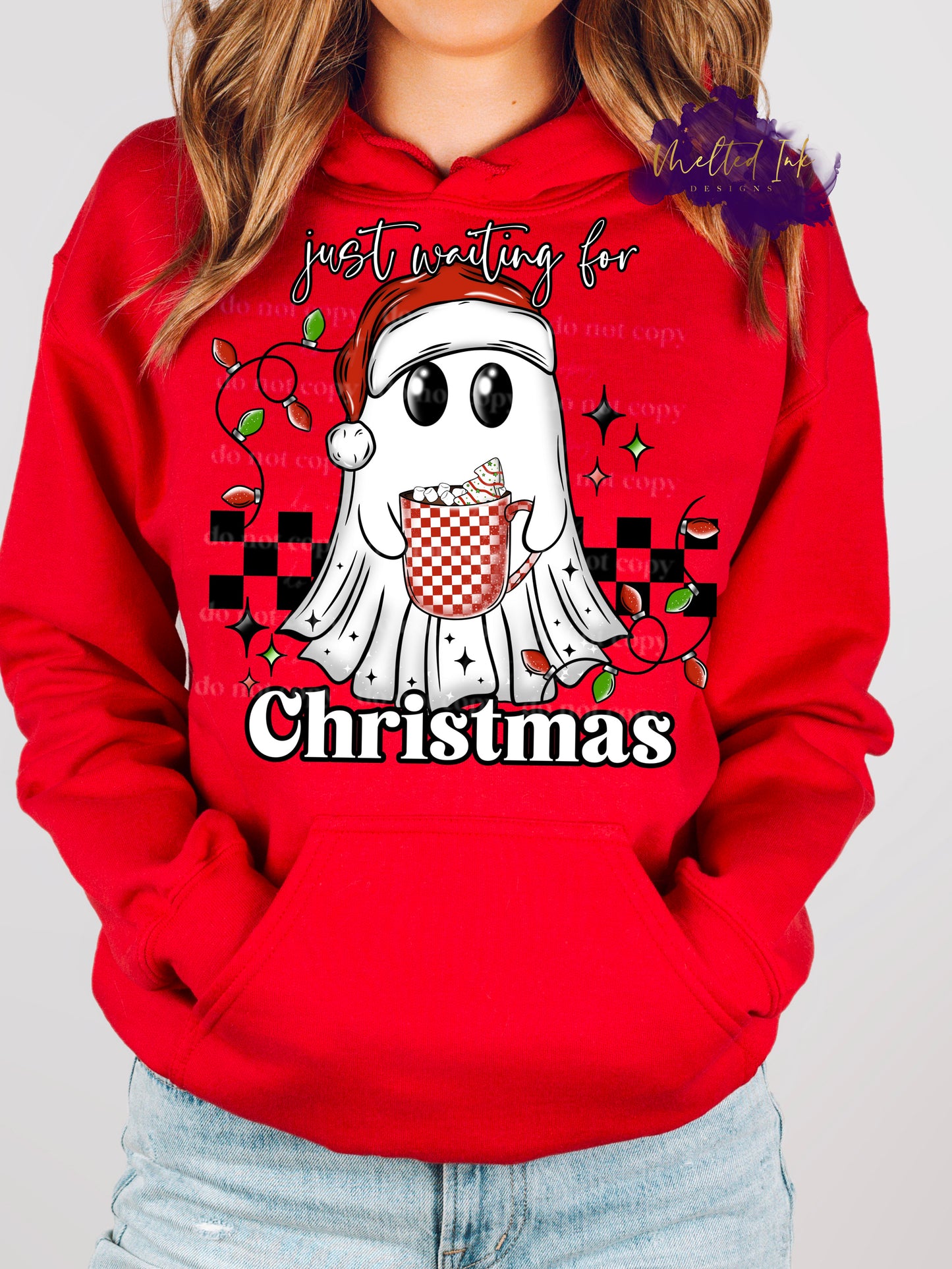 Design is a mock up and is on a red hoodie. Design is colored and is a picture of a ghost in a santa hat holding a coffee mug in front of a checkered rectangle. Design says Just waiting for Christmas.