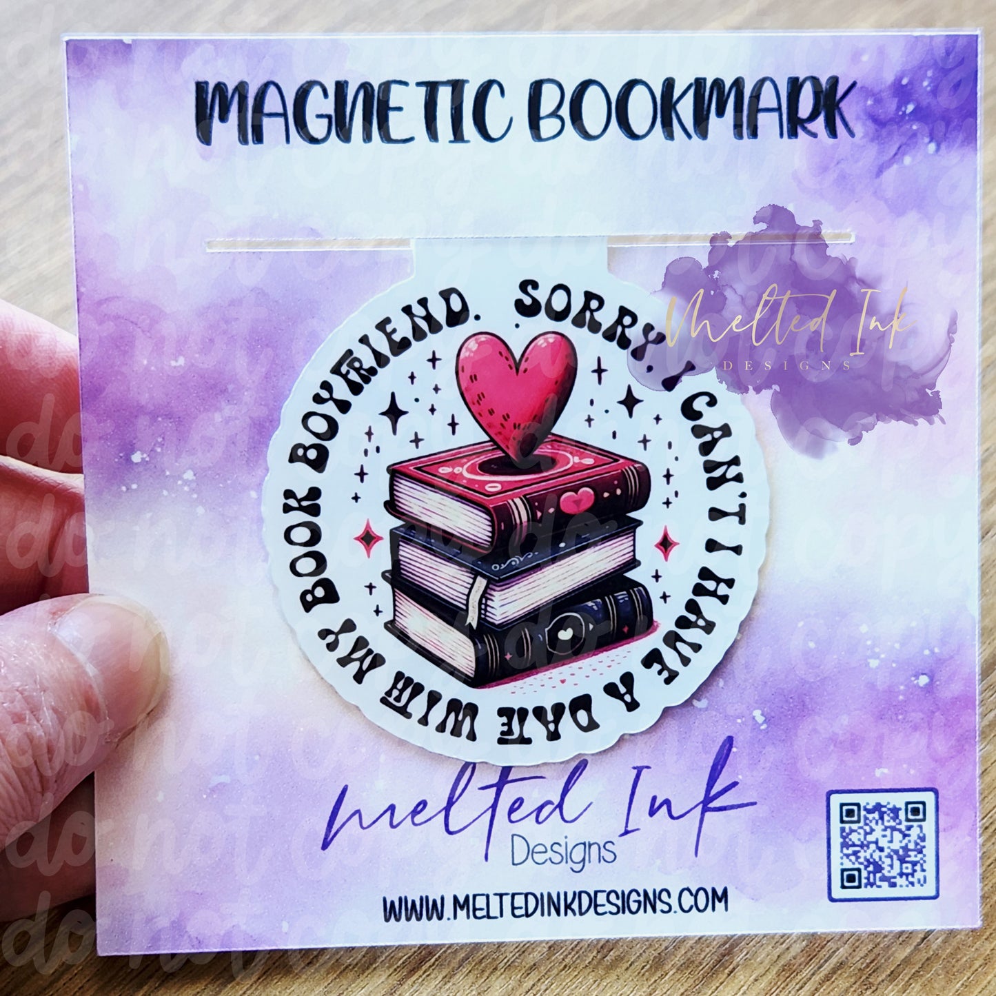 Photo is of a magnetic bookmark that says Sorry I can't I have a date with my book boyfriend in a circle. In the middle of the circle is a stack of 3 books with a pink colored heart.