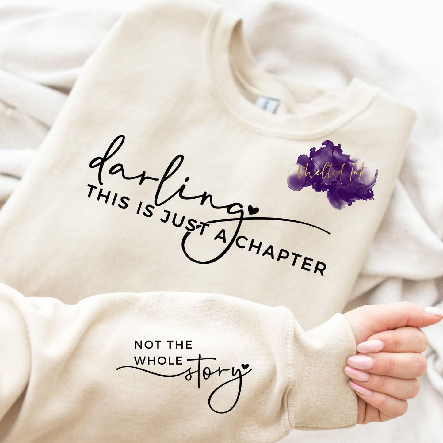Design is a mock up on a sweatshirt and says darling this is just a chapter on the front of the shirt. On the sleeve it says not the whole story.