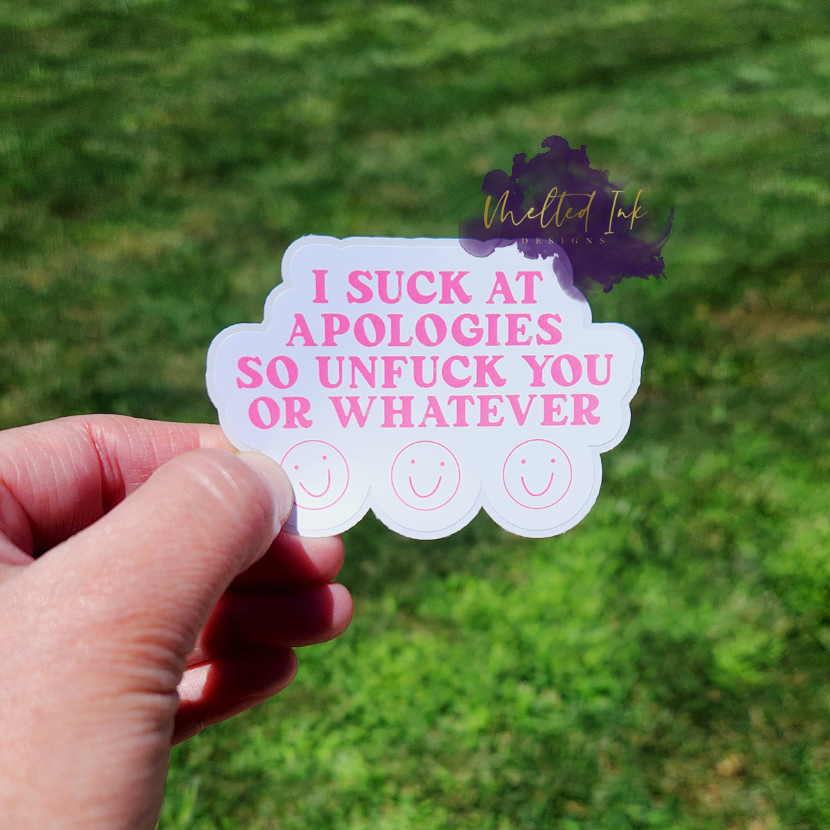 Photo is of a sticker that says I suck at apologies so unfuck you or whatever. Has 3 smiley faces under the words and is in pink ink.