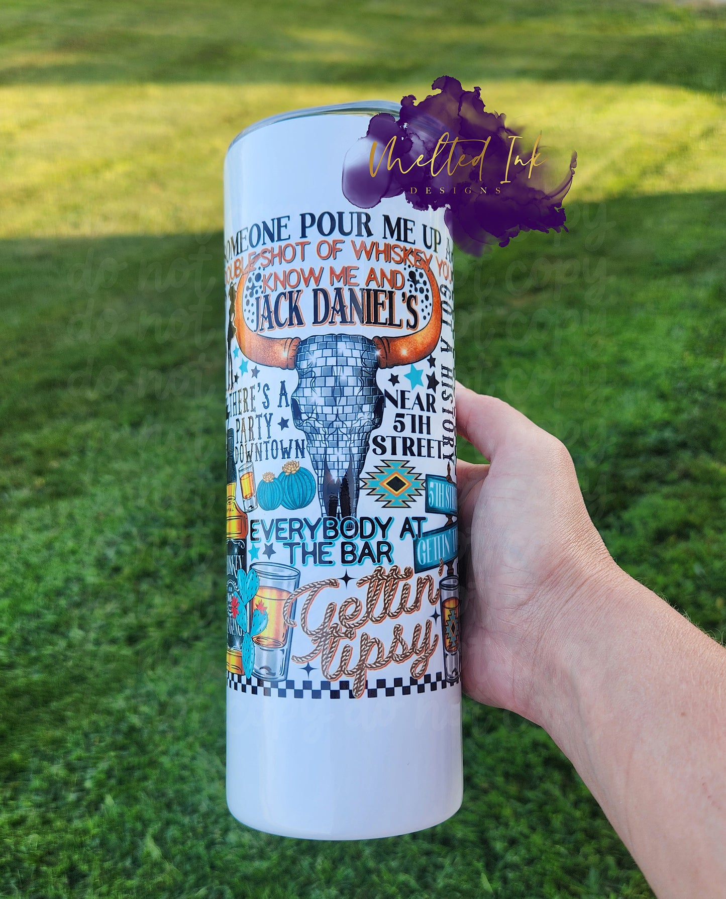 photo showcases a 20oz tumbler that features lyrics from the song "Gettin' Tipsy." The design is accentuated with eye-catching elements related to alcohol, such as drink icons or bottles, and includes a striking cow skull, adding a rustic and bold touch.