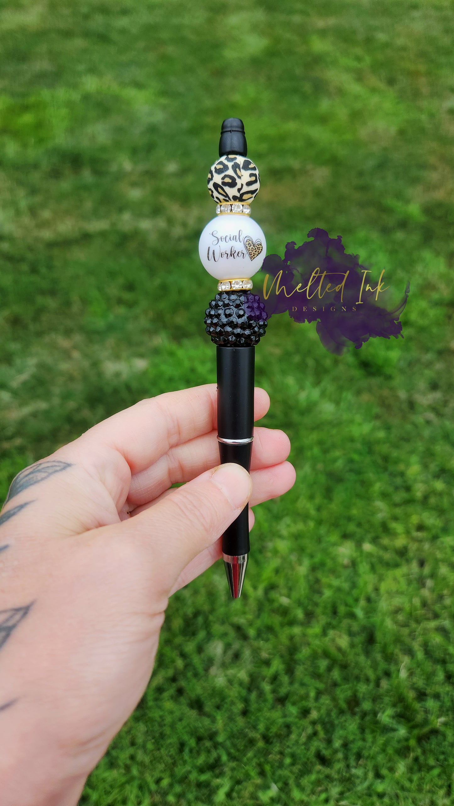 Photo is a black beaded ink pen that has an acrylic bead that says social worker with a leopard print heart. Accenting the acrylic bead is a leopard print silicone bead and a plane black acrylic bead. Also has a rhinestone spacer. Ink is black.