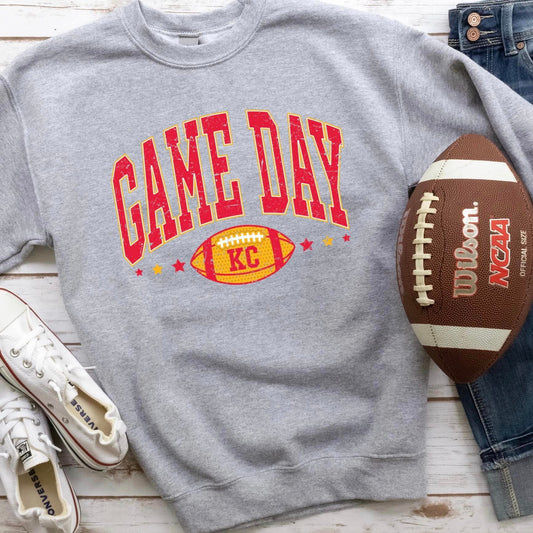 The product photo provided is only a mock up of the design. The design print is red/gold in color and says Game Day. Underneath the word Game Day is a yellow football and the letters KC is wrote on top of the football.