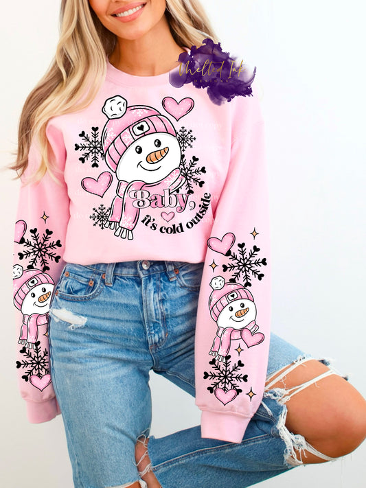 Photo is a mock up of design. Design is of a snowman with a pink hat and scarf. It says Baby it's cold outside. Has snowflakes and pink hearts in the background. 