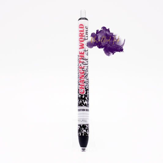 Photo is an epoxy pen that says change the world one child at a time on a composition book style pen wrap. Ink is black. 