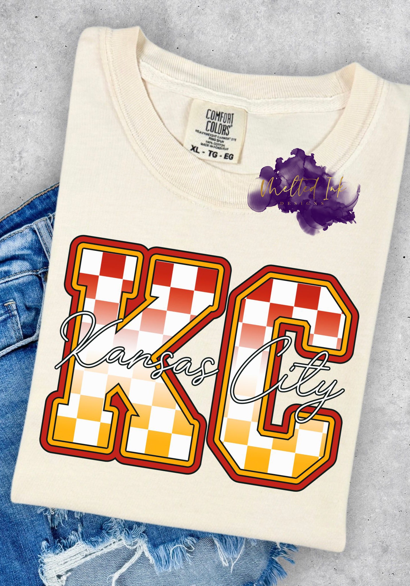 Shirt design with large red, gold, and white checkered “KC” letters outlined in bold black and yellow. A cursive “Kansas City” script overlays the design. A sporty and stylish Kansas City-themed graphic for shirts, sweatshirts, and hoodies.
