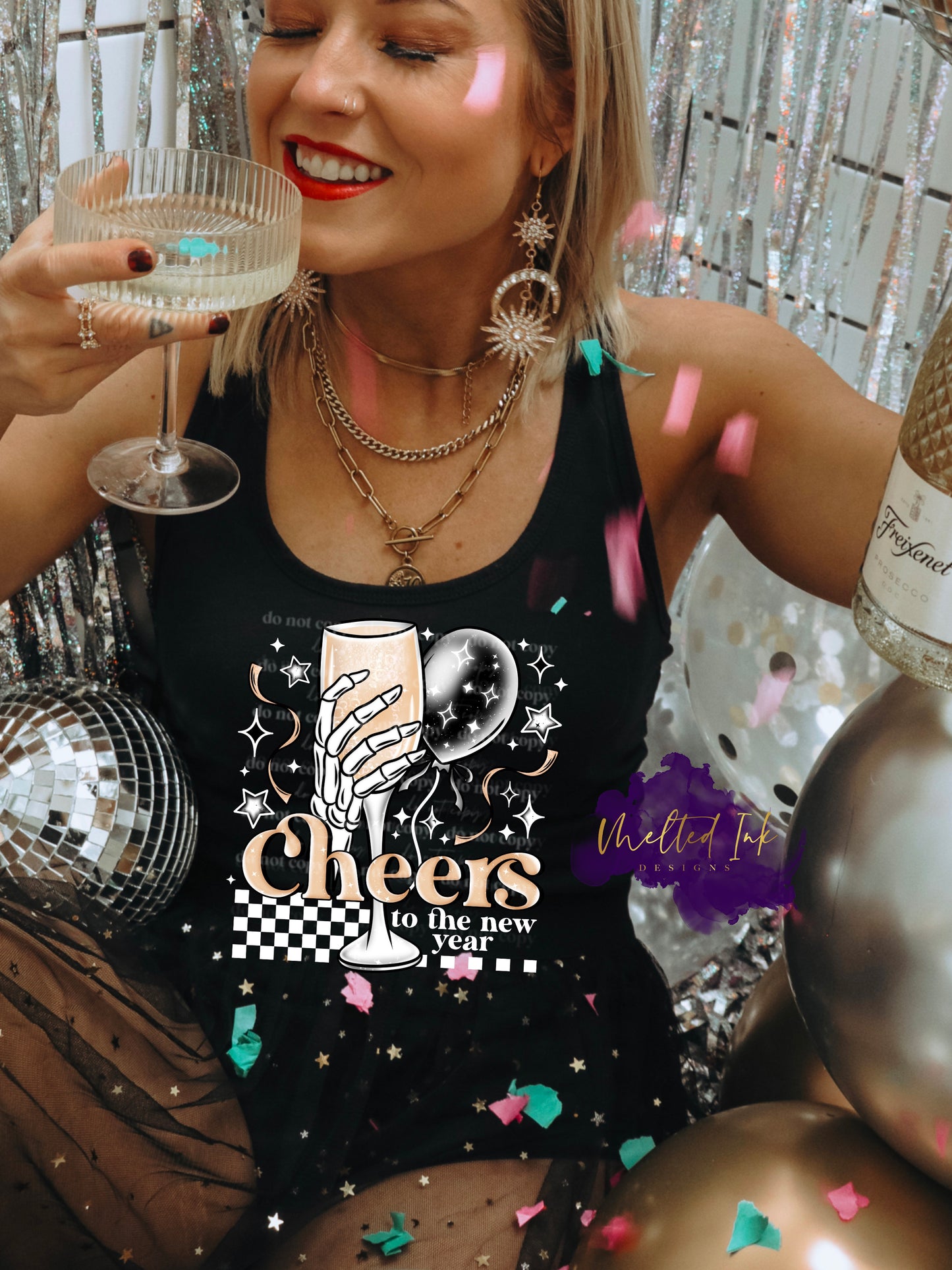 Photo is a mock up of design. Design is on a black shirt and says Cheers to the new year. Has a skeleton hand holding a wine flute with a balloon and confetti. 