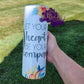 Photo features a 20oz tumbler that says let your heart be your compass. Shows a compass sign and has yellowish red lilly flowers. 