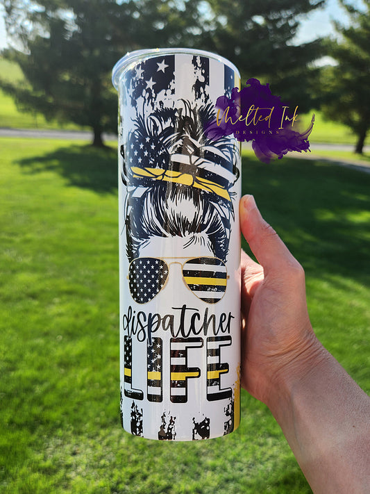 Photo consists of a 20oz tumbler that shows a girl with her hair up on a bun wearing a thin yellow line flag headband. She is also wearing sunglasses that show the thin yellow line flag. The cup says dispatcher life. The thin yellow line flag is also wrapped around the tumbler. 