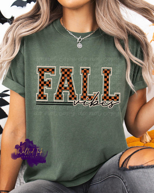 Photo is a mock up of the design. Design is a colored design and is pressed on a moss green colored shirt. The design says Fall Vibes. The word Fall is black and orange checkered. 