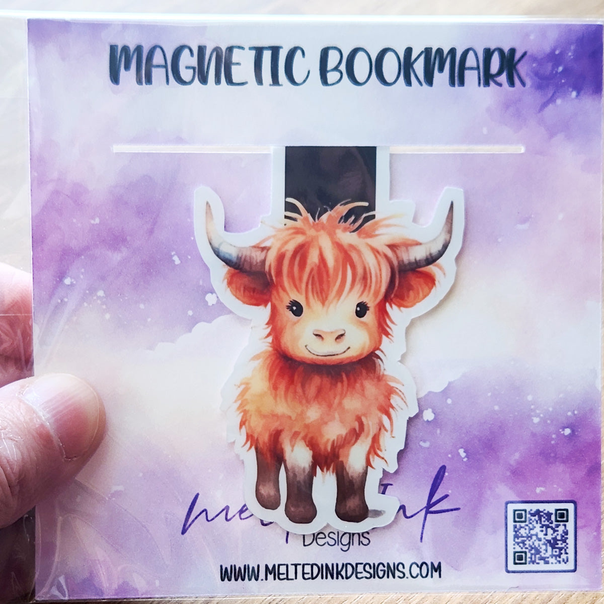 This magnetic bookmark features a charming illustration of a tan Highland cow, known for its long hair and gentle demeanor. 