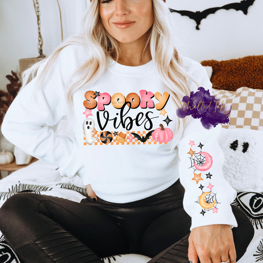 Photo is a mock up of the design. Design print is colored with orange, pink and black. Design says Spooky Vibes and has a orange checkered underneath the words. Over top of the checker design is a little ghost, bat, pumpkin, candy corn and circle piece of candy. Also pictured is the option to have a sleeve print design which consists of half pink crescent moon over a spider web and half yellow crescent moon over a spider web and has orange, black and pink stars around design. 