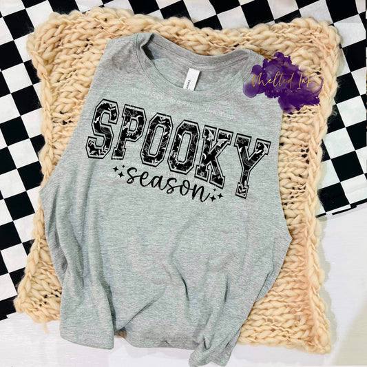 Photo is a mock up of the design.  Design is a black print pressed on a gray shirt. Design says Spooky Season. The word spooky has a bat background inside of them. 