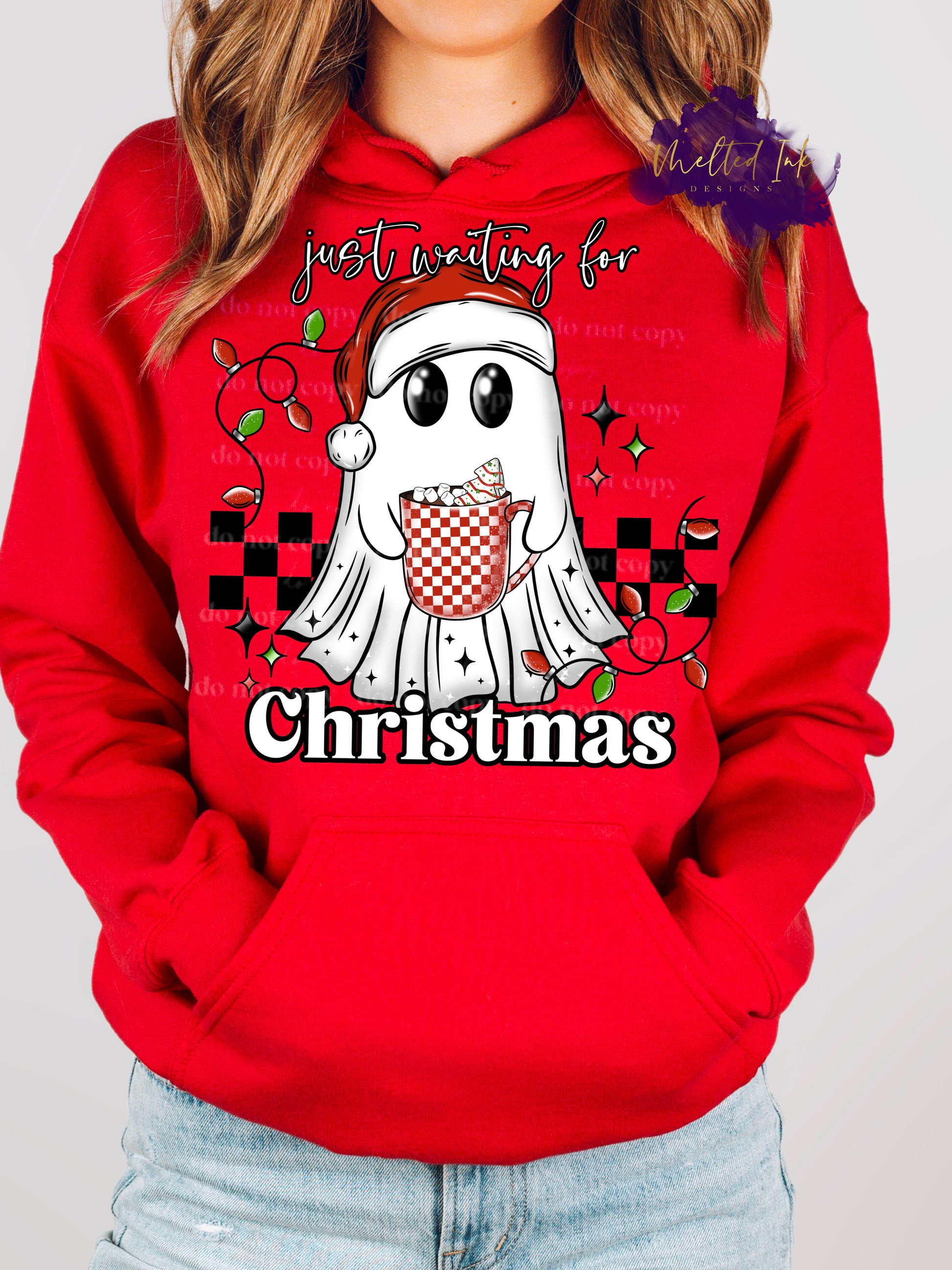 Design is a mock up and is on a red hoodie. Design is colored and is a picture of a ghost in a santa hat holding a coffee mug in front of a checkered rectangle. Design says Just waiting for Christmas. 