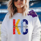 Photo is a mock up of design. Design is of the letters K and C. The K is red and yellow for KC Chiefs colors and the C is light and dark blue for the KC Royals. The letters are a faux glitter leopard print and across the letters the design says Kansas City in black. 