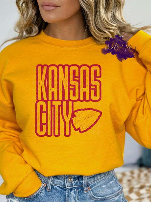 Photo is a mock up of a design. Design is red with red splatters and says Kansas City with an arrowhead. 