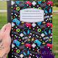 Gaming notebook with colorful controllers, headsets, and gamer text on a black background.
