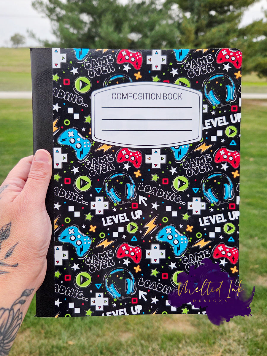 Gaming notebook with colorful controllers, headsets, and gamer text on a black background.