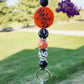 This Halloween lanyard features a fun focal bead that reads "Look, It's Frickin Bats" on one side and "I Love Halloween" on the other. It includes four 15mm silicone beads: a pearl black bead, a pearl orange bead, and two bat-themed beads—one white with black bats and the other black with white bats. The design is enhanced with rhinestone spacers, adding a touch of sparkle, and it comes with a keyring for practicality.