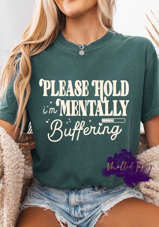 A a shirt with the phrase “Please Hold I’m Mentally Buffering” in playful retro lettering with a small loading bar illustration. A funny and relatable design perfect for shirts, sweatshirts, and hoodies.