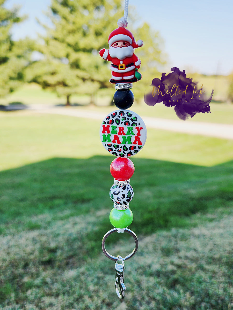 This Christmas lanyard features a fun Santa focal bead and a "Merry Mama" focal in festive green and red leopard print. The design includes red and green pearl silicone beads, decorative spacers, and additional green and red leopard print silicone bead, all contributing to a playful and stylish look. Keyring is included. 