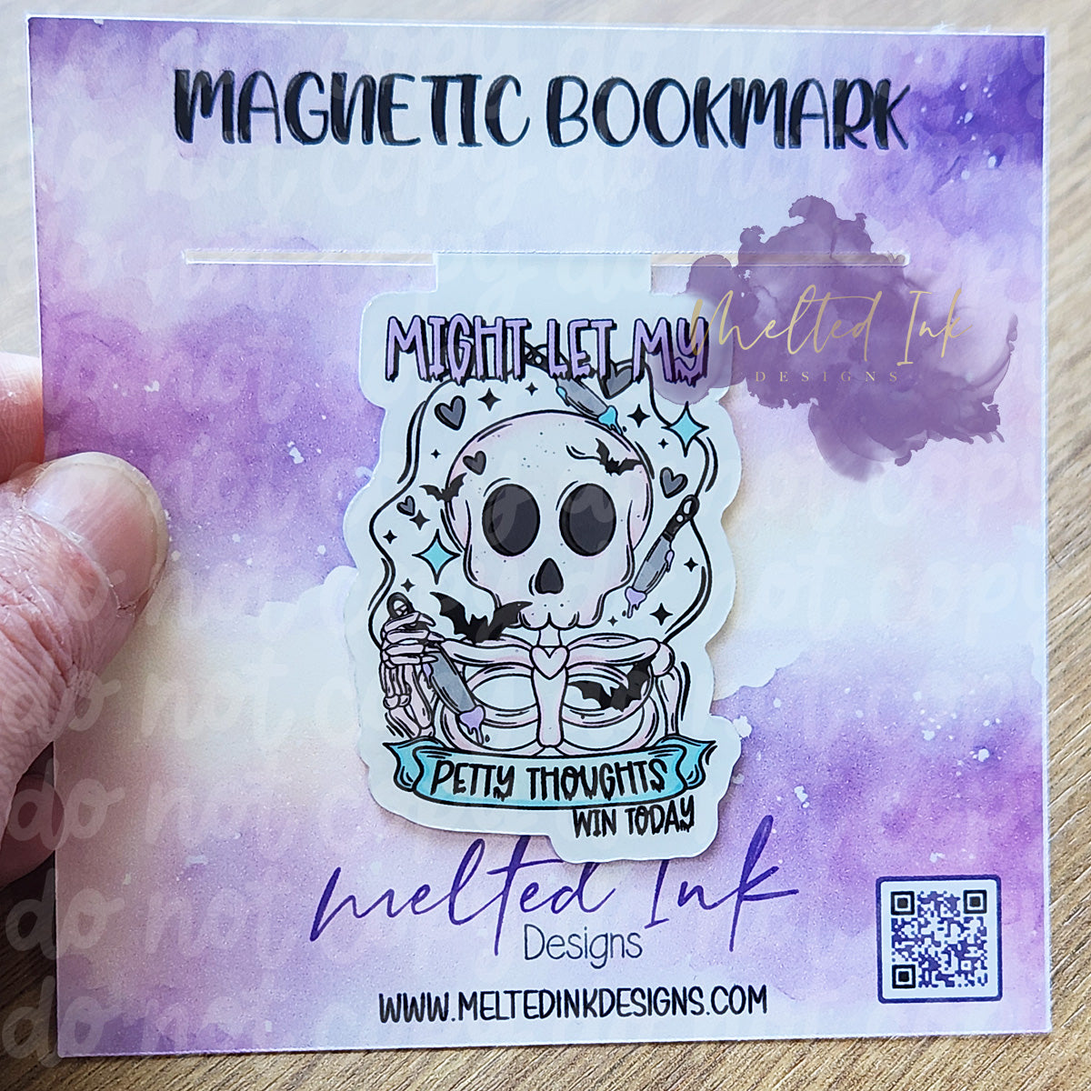 This magnetic bookmark has a bold and humorous design that reads, "Might let my petty thoughts win today." It features a quirky skeleton holding a knife, with additional knives floating in the background, adding to the playful yet edgy vibe.