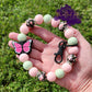 Photo is a keychain wristlet that includes several 15 mm silicone beads that are pink floral print with light pink and mint. Includes a pink monarch butterfly focal bead and has a black keyring. 