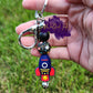 photo is a silver beadable keychain bar that has a solid black and planet silicone beads. also has a spaceship on the bottom