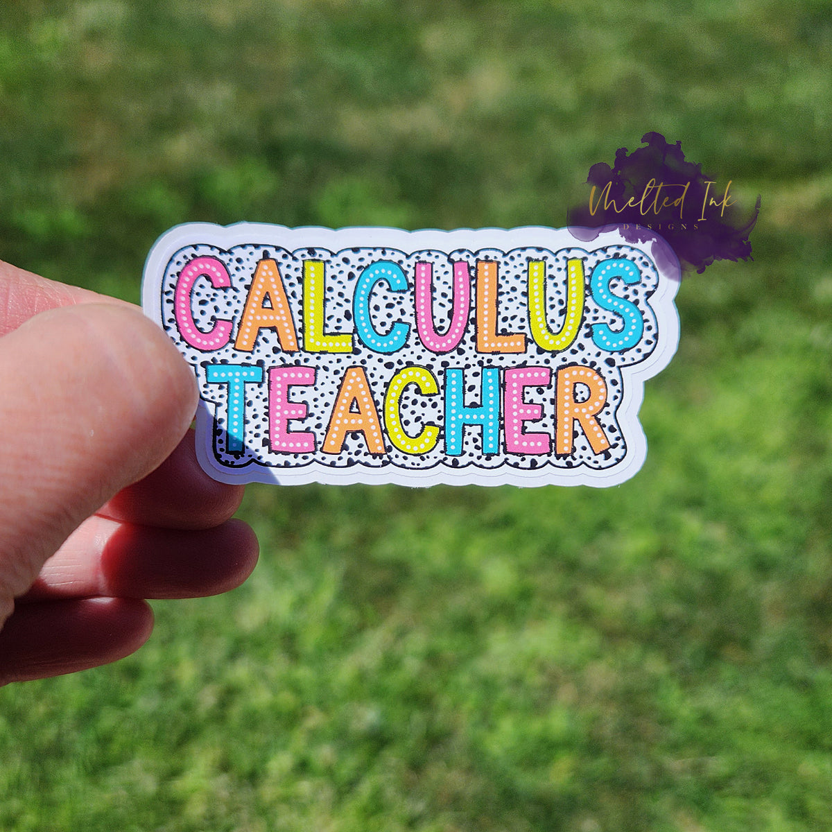 Photo is of a sticker that says calculus teacher and has a black polka dot outline around it. 