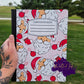 Christmas notebook with Santa faces, ornaments, and stockings on a pink background.
