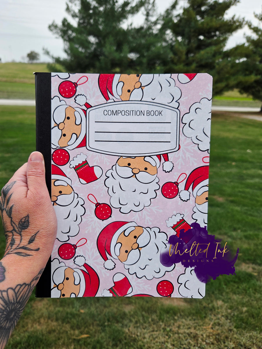 Christmas notebook with Santa faces, ornaments, and stockings on a pink background.