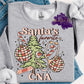 Photo is a mock up of design. Design is colored light pinks and light green and says Santa's Favorite CNA. Has picture of a christmas tree, ornaments, candy cane, stethascope and bandaid. 