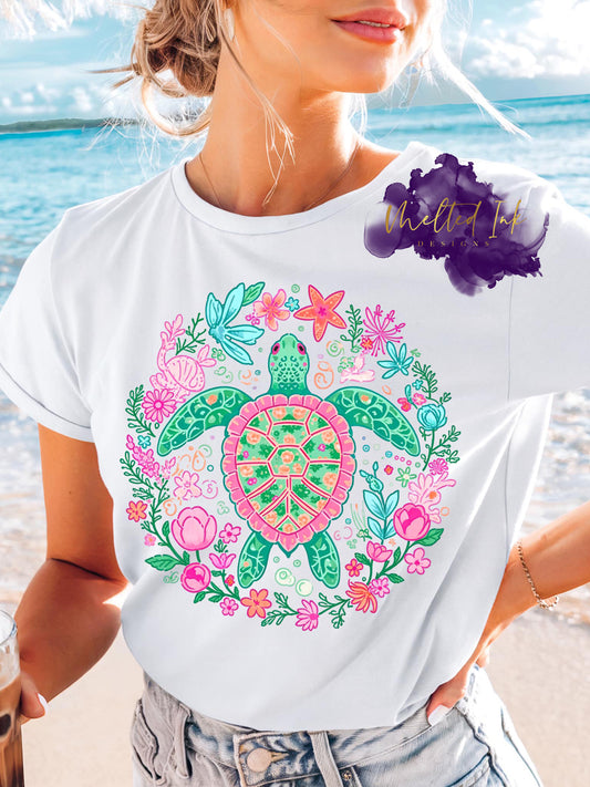 Shirt design featuring a vibrant sea turtle surrounded by colorful tropical flowers, coral, sea stars, and ocean leaves in a circular marine life design.