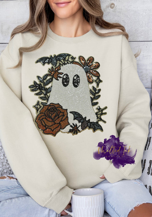 Image of a friendly ghost made entirely of sequins, surrounded by bronze and black floral details, green leaves, and two small bats. The design sparkles under the light, blending spooky and elegant elements in an autumn-themed style.