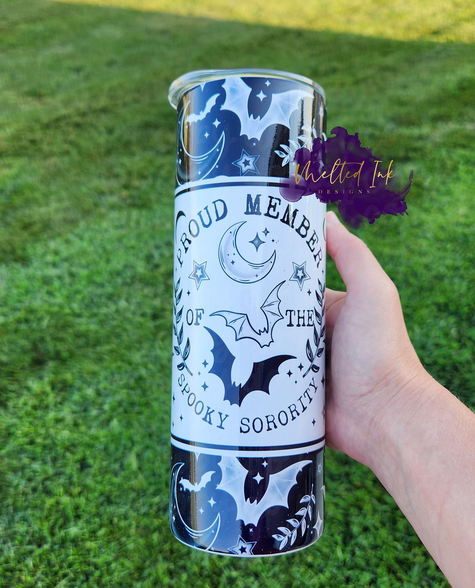 Photo consists of a 20oz halloween theme tumbler that says proud member of the spooky sorority. It has moon, bat and star elements throughout the design. 