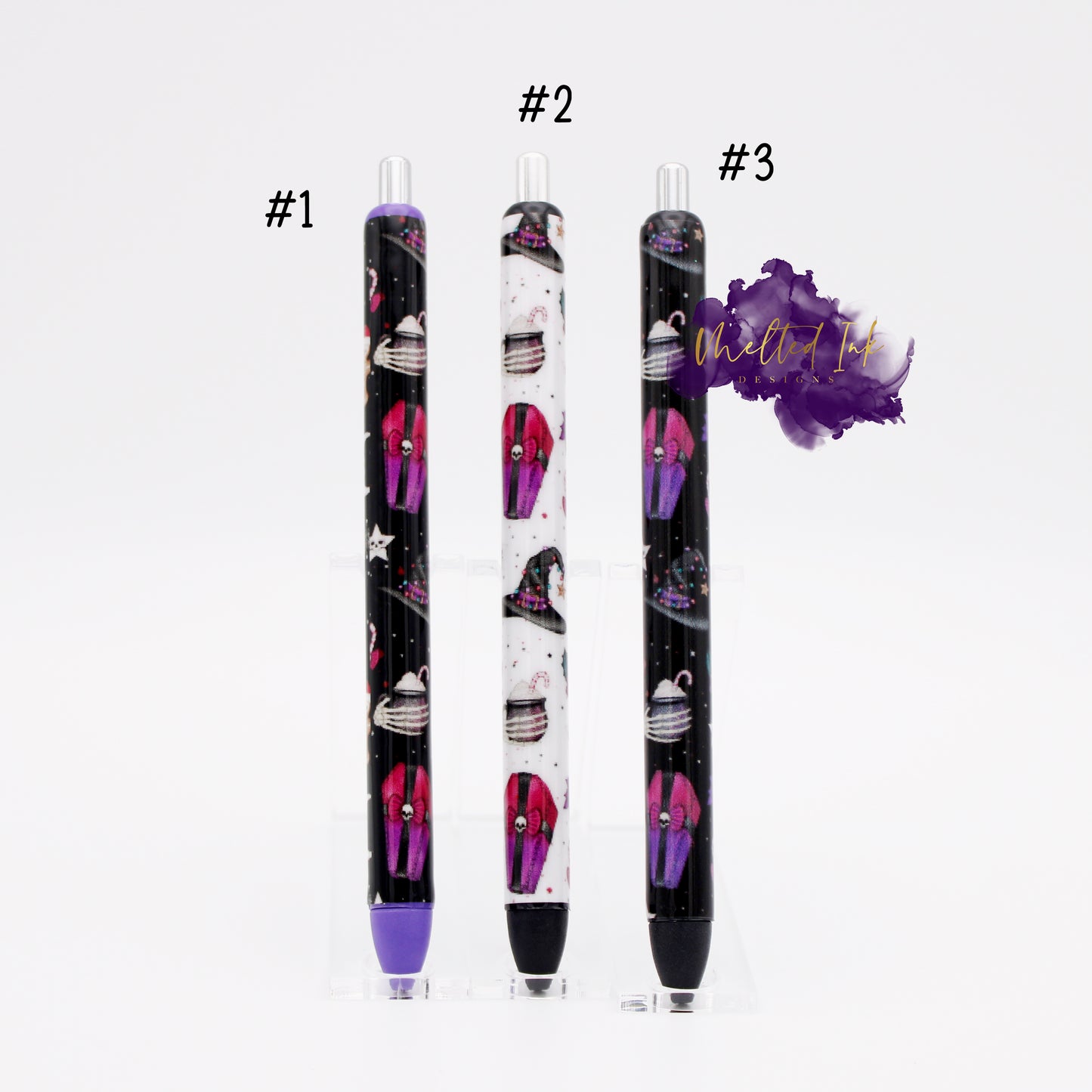 Photo consists of 3 different epoxy pens. All designs are the same which includes a spooky halloween theme with a coffin, witch hat, skeleton hand holding a coffee, etc. #1 pen has a black background and has purple tip which has purple ink. #2 has a white background with black ink and #3 has a black background with black ink. 