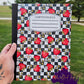 Strawberry notebook with black and white checkerboard background and floral details.