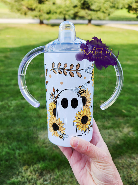 Photo consists of a kids sippy cup that converts into a tumbler. The design on the cup consists of a sunflower ghost with bees. 