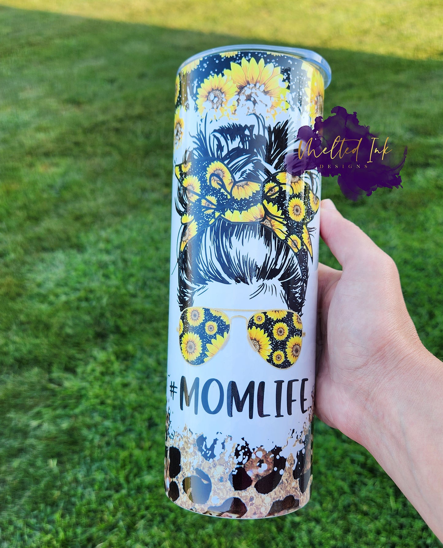 Photo consists of 20oz tumbler. The background consists of sunflowers and leopard print. The center design is of a girls head that has her hair up in a bun wearing a sunflower headband and sunflower sunglasses. 