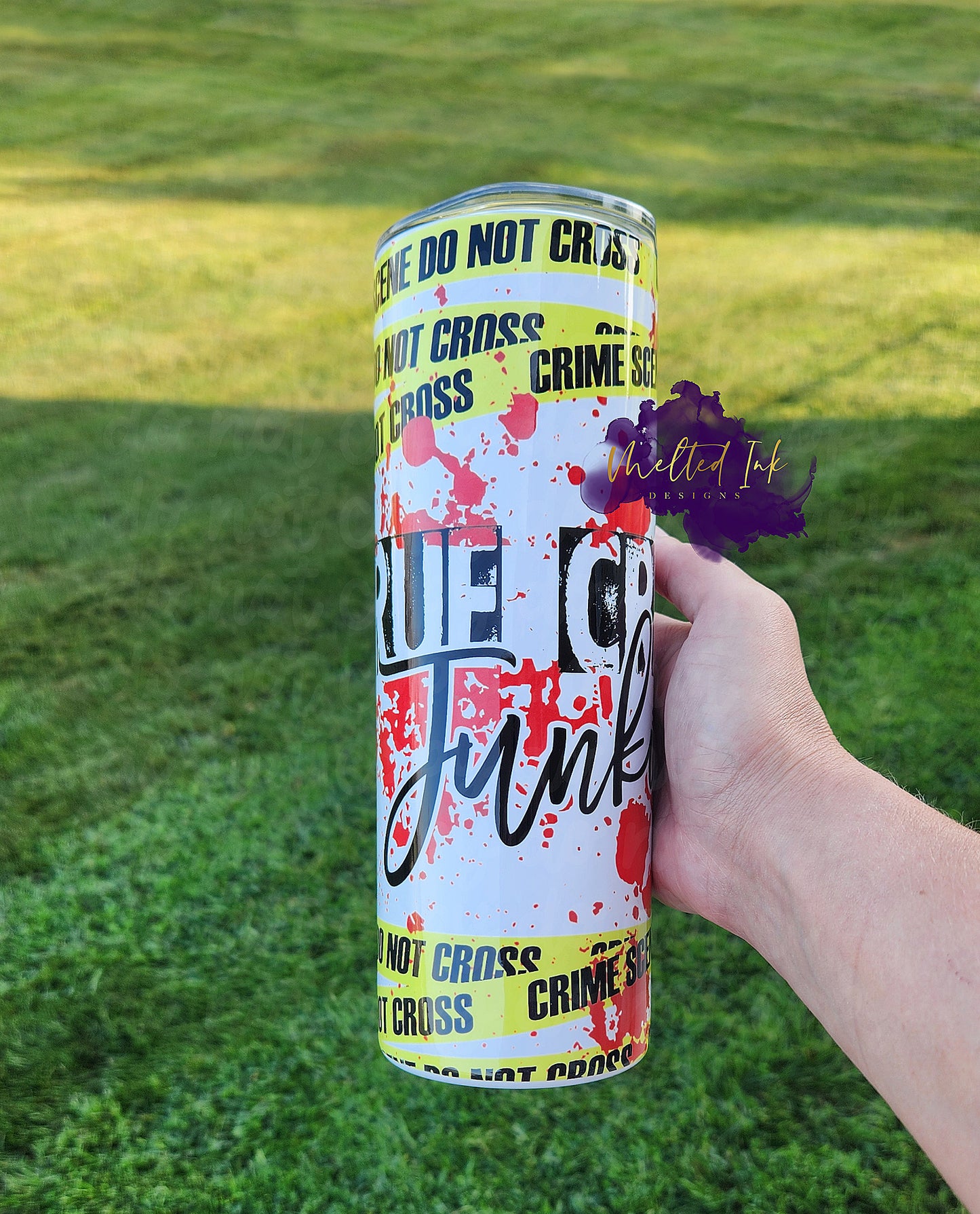 Photo is  a 20oz tumbler that says True Crime Junkie. It features crime scene tape and blood splatters. 