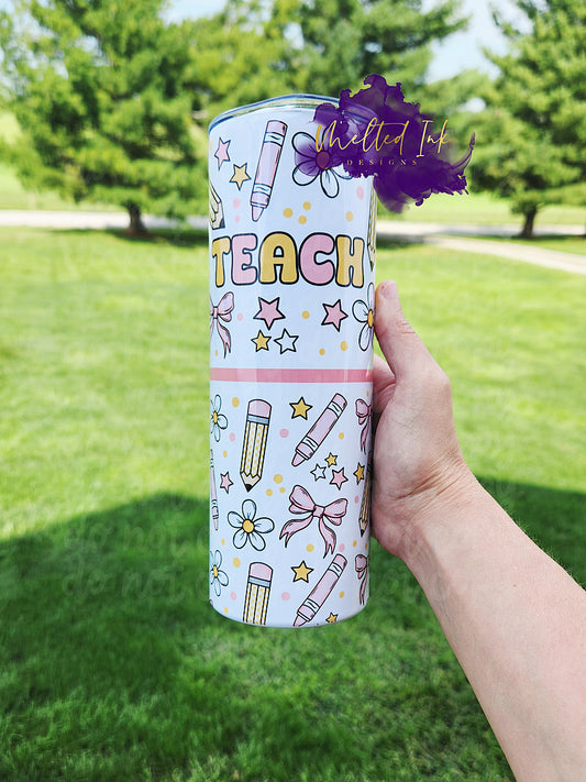 The photo features a 20oz teacher tumbler designed with a vibrant and playful theme. It showcases light pink crayons and yellow checkered pencils, adding a fun educational touch. Adorning the tumbler are light pink bows and white flowers, which bring a whimsical and cheerful vibe to the overall design.