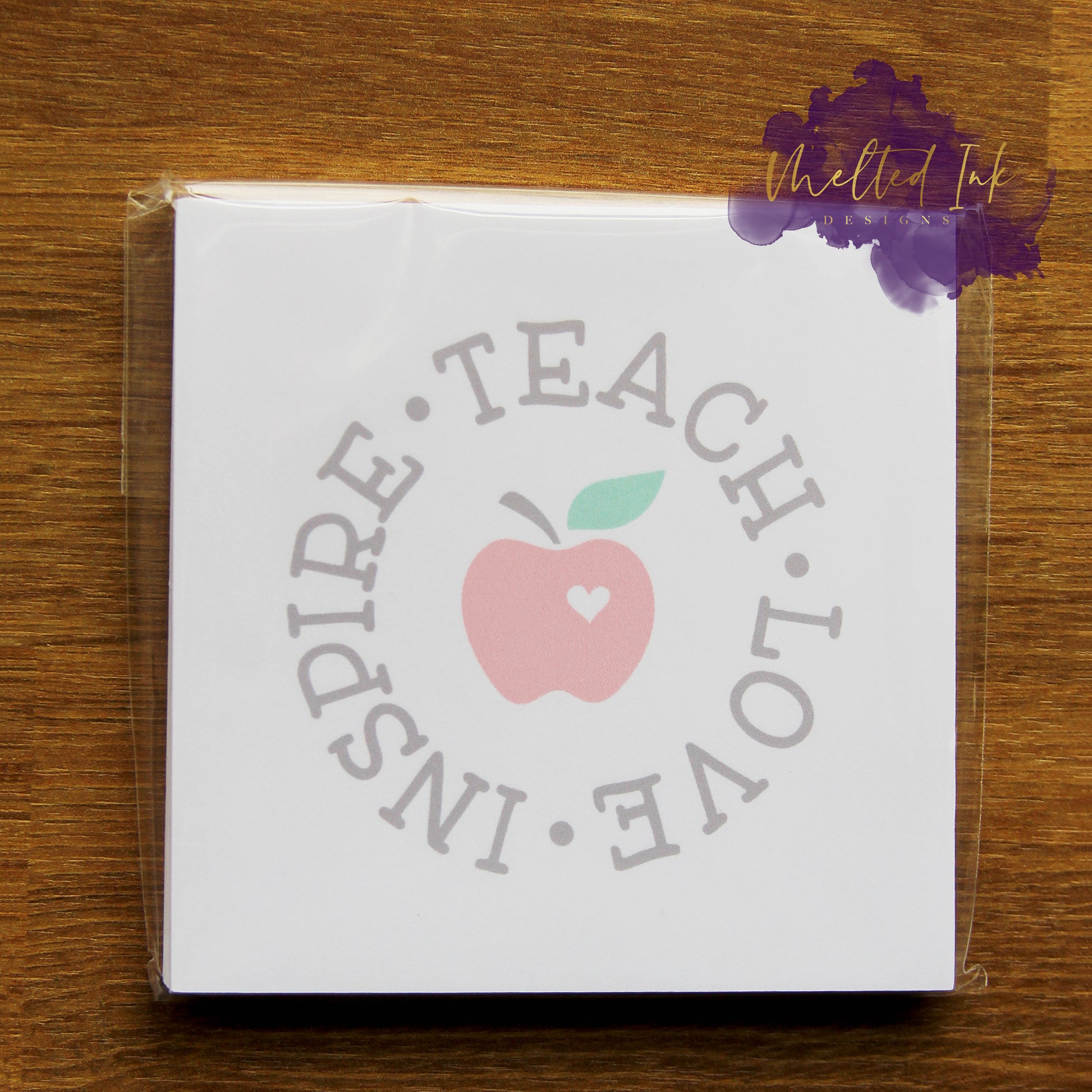 Photo is of a 3.5x3.5 notepad that says teach love and inspire going in a circle with an apple in the middle. 